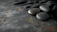 Smooth dark zen stones on textured concrete surface with dramatic side lighting creating moody atmosphere for spa and wellness concept background.