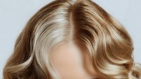 Blonde wavy hair with highlights and lowlights on white background, showcasing professional salon styling for beauty and haircare advertising.