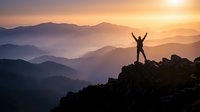 Silhouette of triumphant hiker with raised arms celebrating success on mountain peak at golden sunrise with layered mountain ranges in misty background.