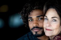 Close-up portrait of happy interracial couple smiling together. African American man with curly hair and beard embracing Caucasian woman outdoors.