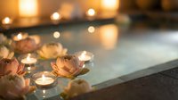 Spa bathtub with floating candles and rose petals creating romantic wellness atmosphere for relaxation and self-care rituals at luxury resort.