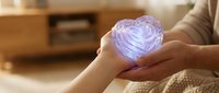 Hands holding glowing purple heart symbol representing love, care, compassion and emotional wellness in warm indoor setting for health concepts.