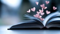 Open book with pink paper hearts floating above pages against blurred blue background, creating romantic and dreamy atmosphere for love stories and literature concepts.