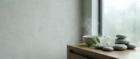 Spa wellness setup with stacked stones, white orchid flower, and natural light from window on wooden shelf for relaxation and meditation themes.