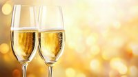 Two champagne flutes filled with sparkling wine against a warm golden bokeh background, perfect for celebration, toast, and festive event designs.