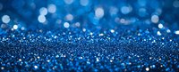Shimmering blue glitter background with bokeh effect creates magical festive atmosphere, defocused sparkles scatter across dark surface in panoramic view.