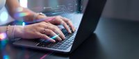 Professional hands typing on modern laptop with digital network connections and colorful light effects in contemporary workspace environment.