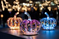 Decorative glass pumpkins with internal LED lights creating magical bokeh effect in orange, purple, and blue colors against dark background with glowing lights.