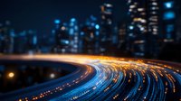 Curved highway with light trails at night, blurred city skyline in background creates dynamic urban scene with blue and orange streaks from vehicle movement.