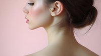 Side profile of young Asian woman with elegant makeup and updo hairstyle against pink background, showcasing natural beauty and feminine features for cosmetic and beauty industry.