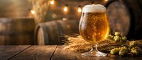 Fresh craft beer glass with foam on rustic wooden table with hops and barrels in warm brewery atmosphere for oktoberfest celebration and pub marketing.
