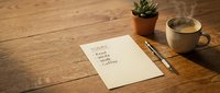 Morning routine planning with handwritten to-do list on wooden desk featuring coffee cup, succulent plant and pen for productivity and organization.
