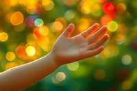 Child's hand reaching toward magical bokeh lights against green and orange blurred background creates dreamy atmosphere for spiritual and hopeful concepts.