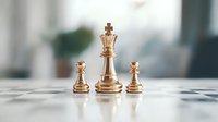 Golden chess pieces on white board with queen in center flanked by two pawns, symbolizing leadership, strategy and hierarchy in business concept.