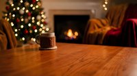 Cozy Christmas living room with decorated tree, warm fireplace and wooden table surface for holiday product display and seasonal home decor concepts.