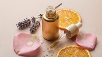 Natural skincare serum with orange citrus and lavender flowers on pink background for beauty wellness aromatherapy spa treatment cosmetics.