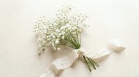 Delicate baby's breath bouquet tied with white silk ribbon on neutral background for wedding decor and romantic celebrations.