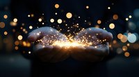 Magical glowing light particles floating between cupped hands against dark background with golden bokeh effect, creating mystical atmospheric scene.