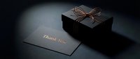 Elegant black gift box with copper ribbon bow and thank you card on dark background, luxury packaging for premium gifting occasions.