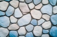 Decorative stone wall pattern in white and blue colors creates calming coastal atmosphere. Smooth rounded rocks form natural mosaic background.