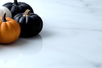 Orange and black pumpkins on white marble background with copy space. Minimal seasonal composition for autumn holiday decoration and design.