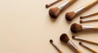 Professional makeup brushes arranged in circular pattern on neutral beige background for beauty and cosmetics applications.