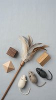 Handcrafted cat toys flat lay with feather wand, felted wool mice, and wooden geometric blocks on a light gray linen background.