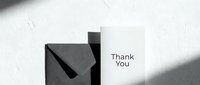 Thank you card with dark envelope on white textured background, minimalist monochrome style with natural shadows for greeting and stationery.