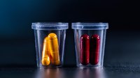 Medical capsules in transparent plastic containers, red and yellow pills on dark background with dramatic lighting. Pharmaceutical storage concept.