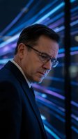 Middle-aged male professional wearing glasses and dark business suit, positioned in profile against glowing blue and purple digital data streams, suitable for technology, business, and corporate concepts.
