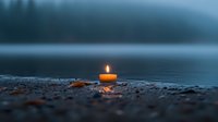 Glowing candle on rocky lakeshore at dusk creates peaceful atmosphere with soft orange flame reflecting on misty water surface, spiritual meditation concept.