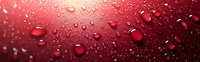 Water drops on red metallic surface with reflective texture creating dramatic contrast between light and shadows in panoramic composition.