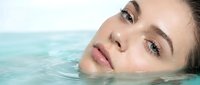 Young woman with natural makeup relaxing in turquoise water spa treatment for wellness skincare routine and beauty therapy relaxation concept.