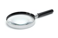 Classic magnifying glass with silver metal frame and black handle isolated on white background for detective work, research, and investigation.