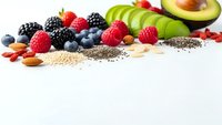 Colorful assortment of fresh berries, avocado, nuts and seeds arranged on white background for healthy eating and nutrition concepts.