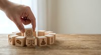 Hand placing wooden cube with gear symbol among blocks showing business icons on wood table representing strategy and organizational development.