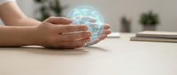 Hands protecting glowing brain hologram on wooden desk representing artificial intelligence, mental health, innovation and futuristic technology concepts.