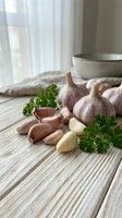 Fresh garlic bulbs and cloves with parsley on rustic wooden table in bright kitchen setting for cooking and culinary preparation.