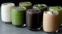 Healthy smoothies in glasses with chia seeds and mint garnish on dark background. Various colors from white to green and chocolate brown show protein drinks.