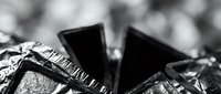 Close-up of shiny black mineral crystals with metallic surfaces and sharp geometric edges, suitable for geology, science education, and industrial material backgrounds.