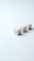 Three white sugar cubes arranged in a row on a clean, neutral background, isolated and ready for culinary, beverage, and food styling design projects.