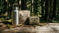 Outdoor survival gear including stainless steel water bottle and first aid kit on wooden surface in forest setting for camping and hiking adventures.