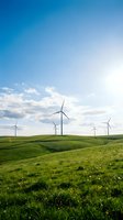 Wind turbines dotting rolling green hills under bright blue sky with white clouds, representing renewable energy and sustainable power generation for environmental projects.