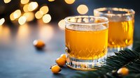 Golden cocktail in crystal glass with festive bokeh lights and orange berries on dark background, winter holiday drink styling for bar and restaurant menu.