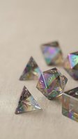 Iridescent polyhedral dice set with rainbow holographic effect on neutral background, for tabletop RPG and board game concepts.