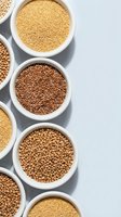 Assorted healthy grains and seeds in white bowls including quinoa, flax seeds, and coriander arranged on light background for cooking and nutrition.