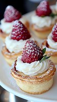 Fresh strawberry tartlets with whipped cream and powdered sugar on flaky pastry shells, perfect for elegant dessert presentations at events.