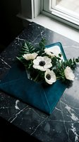 White anemone flowers in teal envelope on black marble surface near window for romantic greeting cards and floral arrangements.