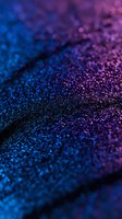 Shimmering blue and purple glitter particles create magical cosmic texture with bokeh effect, macro shot showing detailed sparkles on dark background.