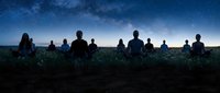 Group of people sitting in meditation pose under starry night sky with Milky Way galaxy visible above peaceful landscape for mindfulness and spiritual practices.